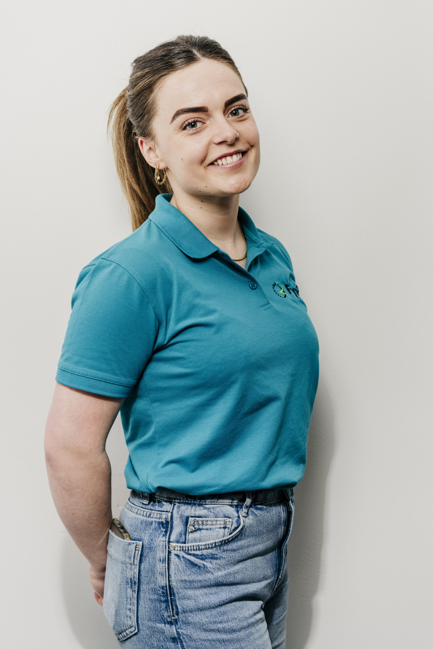 Vriendelijke fysiotherapeut glimlacht in werkoutfit Fysio loon op zand