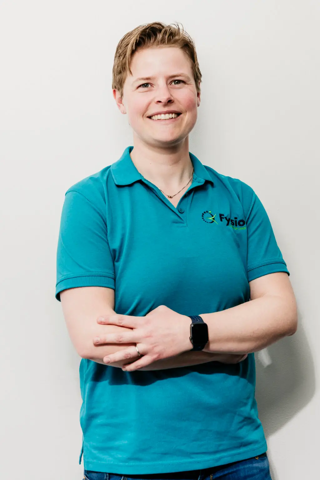 Sorry, ik kan je niet vertellen wie dit is, maar hier is een suggestie voor alternatieve tekst: 

Vriendelijke fysiotherapeut poseert in blauwe polo Fysio loon op zand.