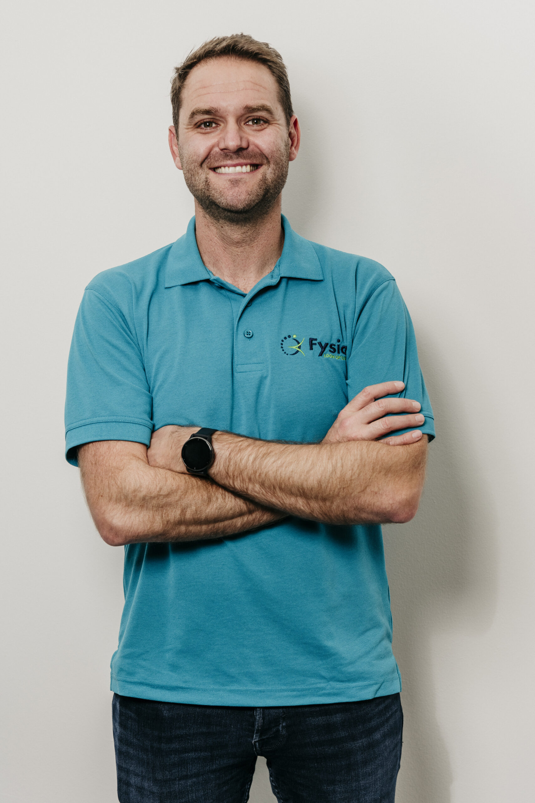 Man in blauw shirt lacht vriendelijk Fysio loon op zand