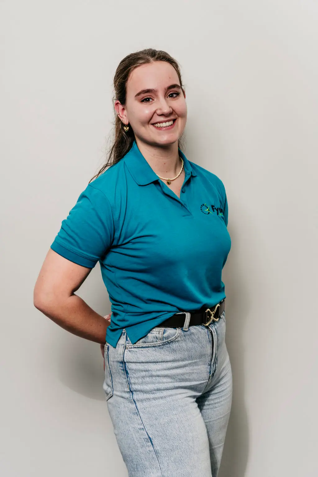 Vriendelijke fysiotherapeut glimlachend in blauwe uniform Fysio loon op zand