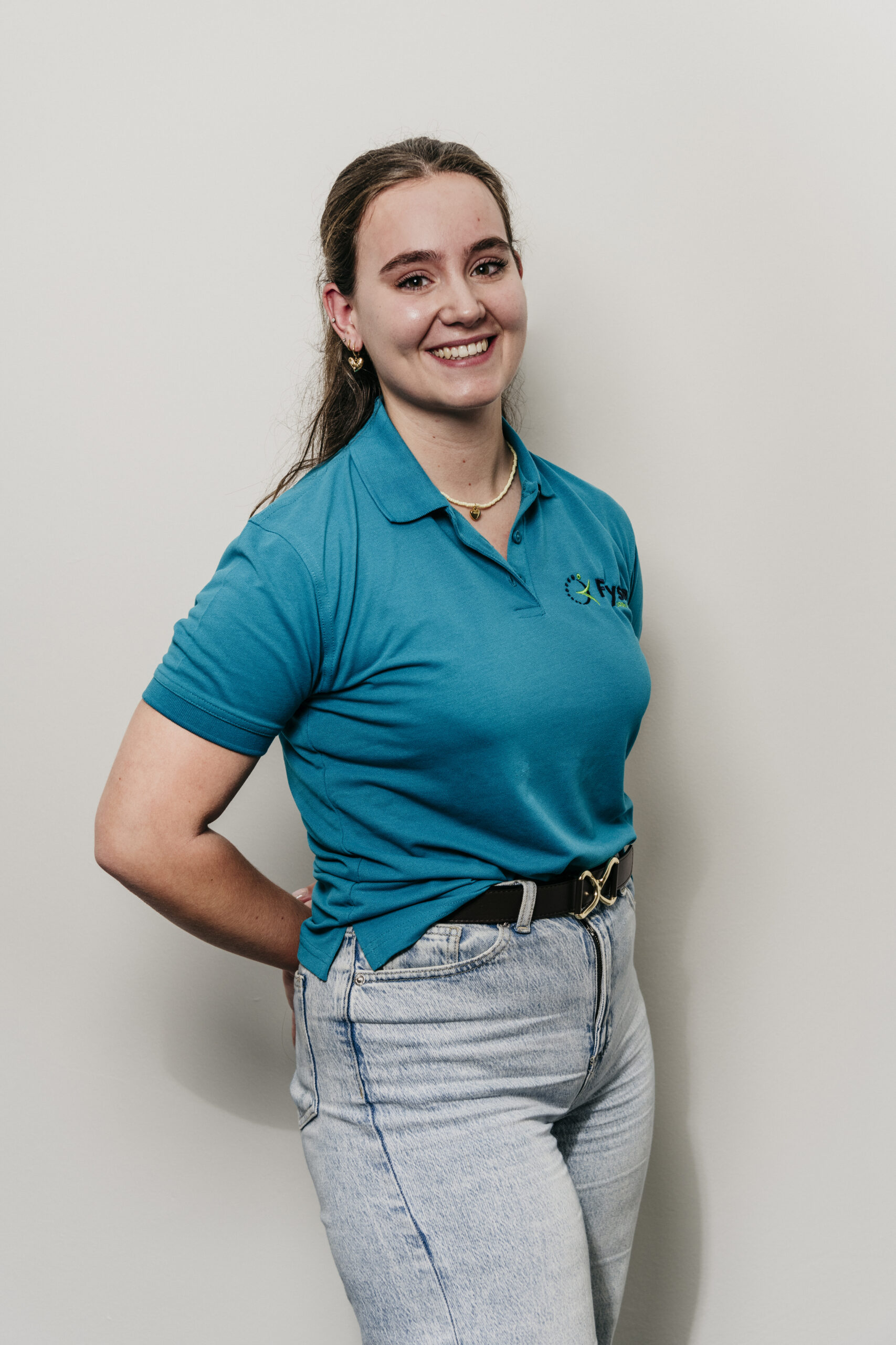 Vriendelijke fysiotherapeut glimlachend in blauwe uniform Fysio loon op zand